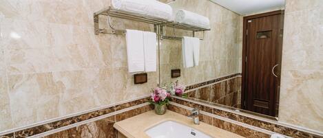 Un baño con lavamanos de mármol, toallero, espejo y puerta de madera.