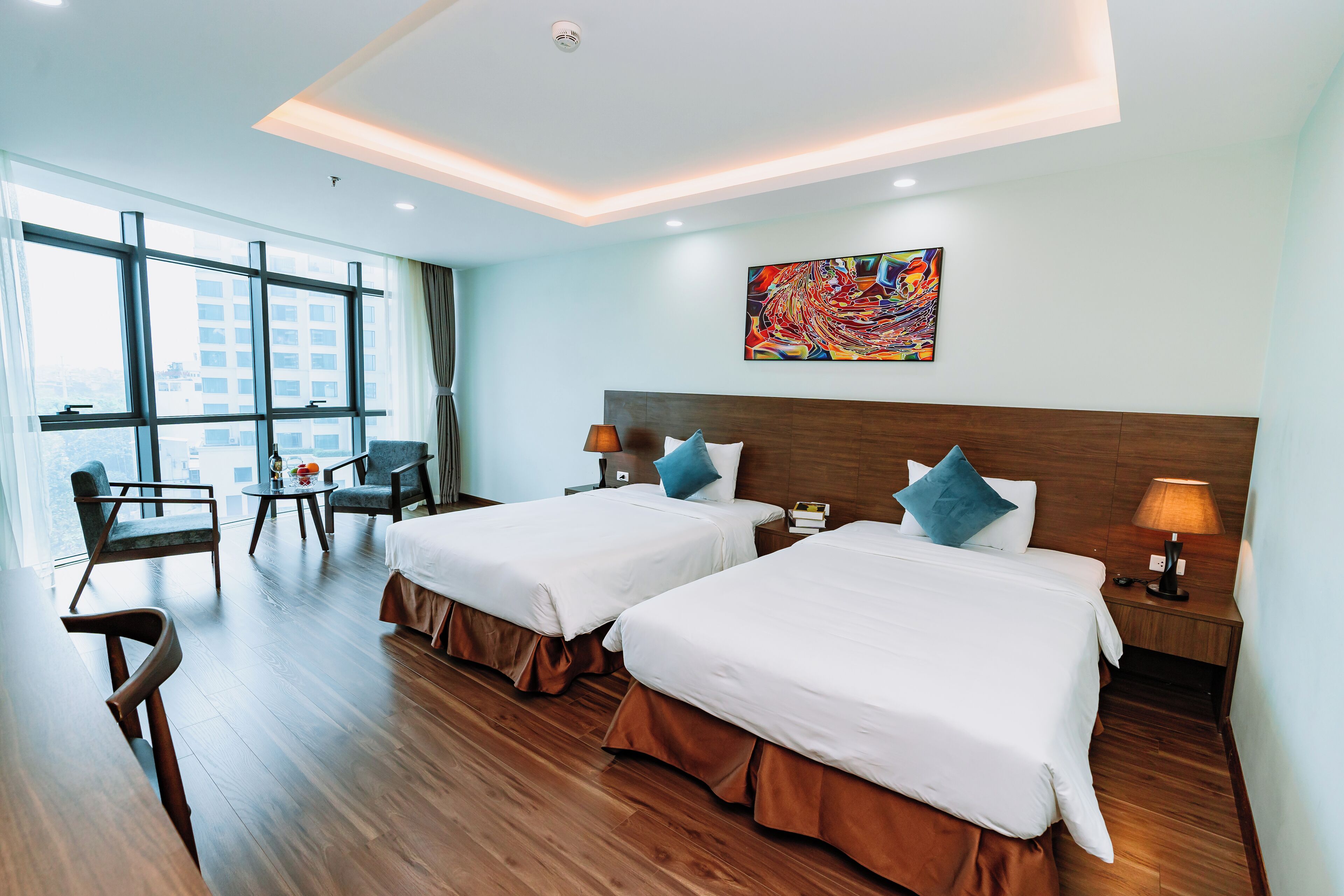 A hotel room with two beds, a desk, and a chair.