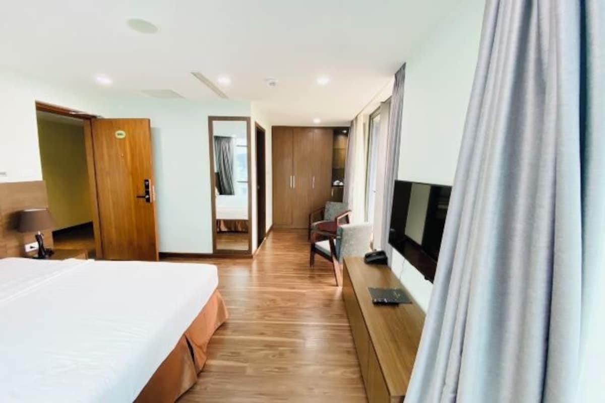 A hotel room with a bed, a desk, a TV, and a wardrobe.