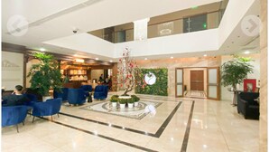 A spacious lobby with a central decorative tree, seating areas, and a reception desk. - Legend Westlake Hotel (Hanoi)