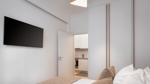 A modern bedroom with a bed, a TV mounted on the wall, and a wardrobe with a mirror. - Athenian Hillside Apartment (Athens)