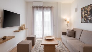 A modern living room with a flat-screen TV, wooden shelves, a sofa, and a coffee table. - Athenian Hillside Apartment (Athens)