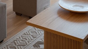 A modern living room with a wooden coffee table, a grey ottoman, and a patterned rug. - Athenian Hillside Apartment (Athens)