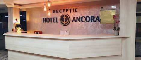 Un mostrador de recepción de hotel con un cartel que dice "RECEPTION HOTEL ANCORA".