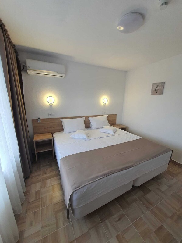 A hotel room with a large bed, two bedside tables, an air conditioning unit, and two wall-mounted light fixtures. - Hotel Ancora (Eforie)