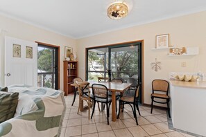 Une pièce comprenant un lit, une table à manger avec des chaises, une bibliothèque et un coin cuisine avec un comptoir.
