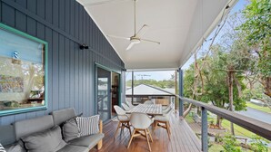 Un espace extérieur aménagé, abrité et doté d’une terrasse en bois, d’un canapé et d’une table avec des chaises.