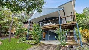 Une maison moderne à deux étages, dotée d’un espace extérieur couvert, d’un escalier et d’un jardin.