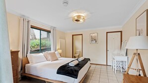 Une chambre d’hôtel avec un grand lit, un bureau, une chaise, une lampe et une fenêtre avec des rideaux.