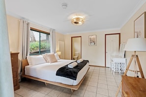A hotel room with a large bed, a desk, a chair, a lamp, and a window with curtains.