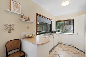 Une cuisine moderne avec des meubles blancs, un four à micro-ondes encastré et une grande fenêtre.