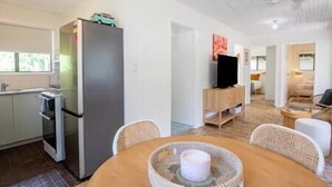 Eine kleine Küche mit Kühlschrank, Backofen und einem Essplatz mit Korbstühlen.