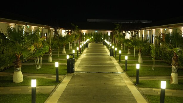 Un sendero bordeado por luces regularmente distribuidas que conduce a un edificio con varias habitaciones.