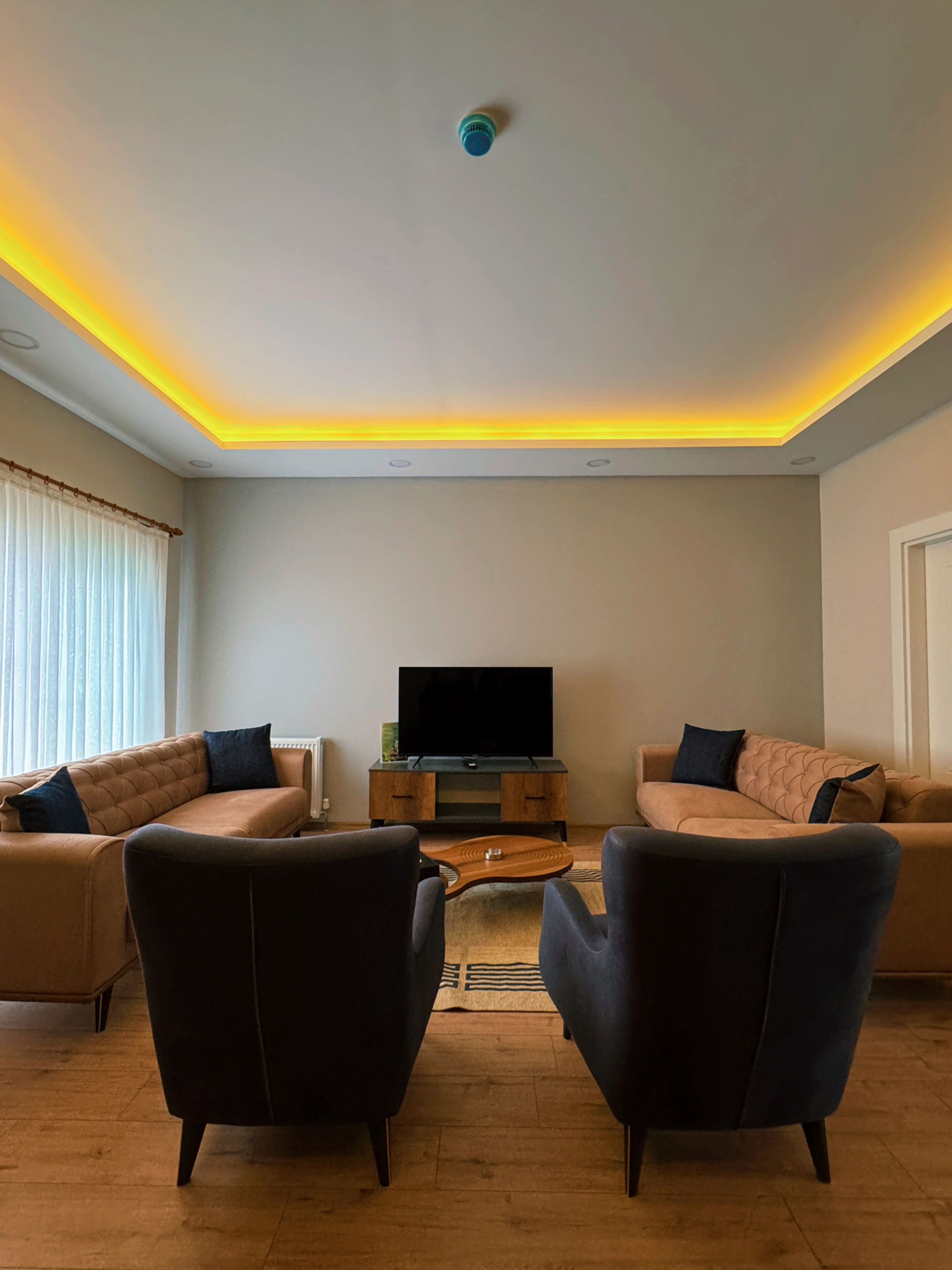 Una sala moderna con dos sofás, una mesa de centro y un televisor de pantalla plana.