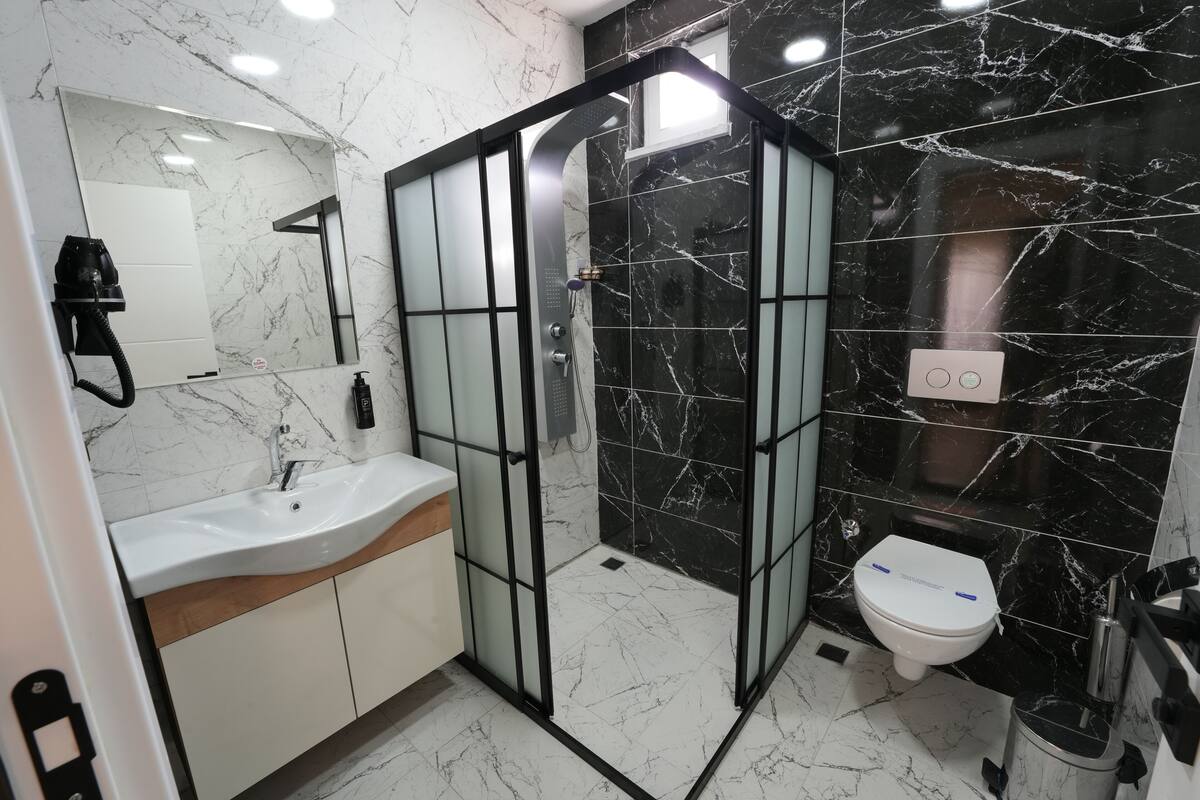 A bathroom with a glass-enclosed shower, a white sink, and a toilet.