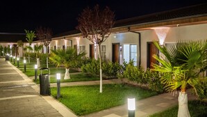 Un pasillo de hotel con senderos iluminados, plantas en macetas y un césped bien cuidado.