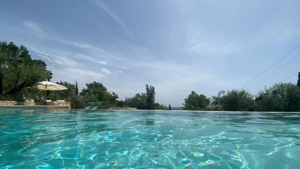 Une piscine aux eaux cristallines, avec vue sur les arbres et un ciel dégagé.
