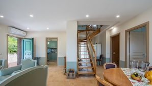 Un vaste espace de vie agrémenté d’un escalier en bois, d’une table à manger avec des chaises et d’une vue sur la cuisine.
