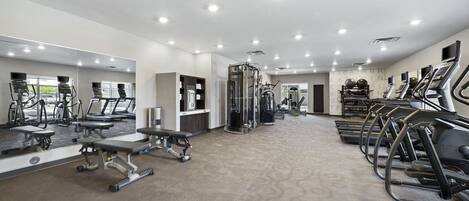 Une salle de sport moderne équipée de tapis de course, d’appareils de musculation et de bancs d’exercices.