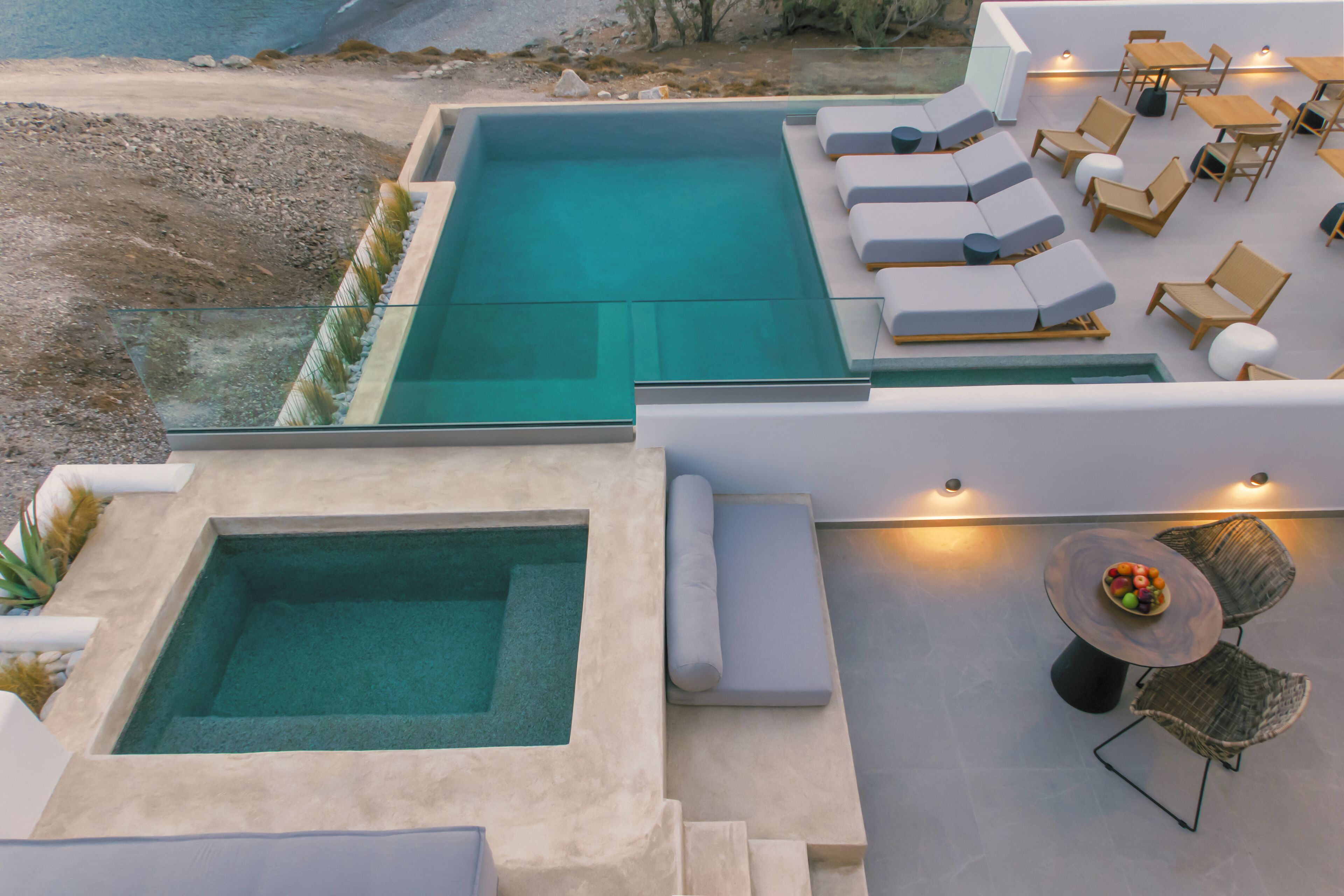 Area piscina sul tetto con una piccola vasca idromassaggio, poltrona relax e un tavolo con frutta.