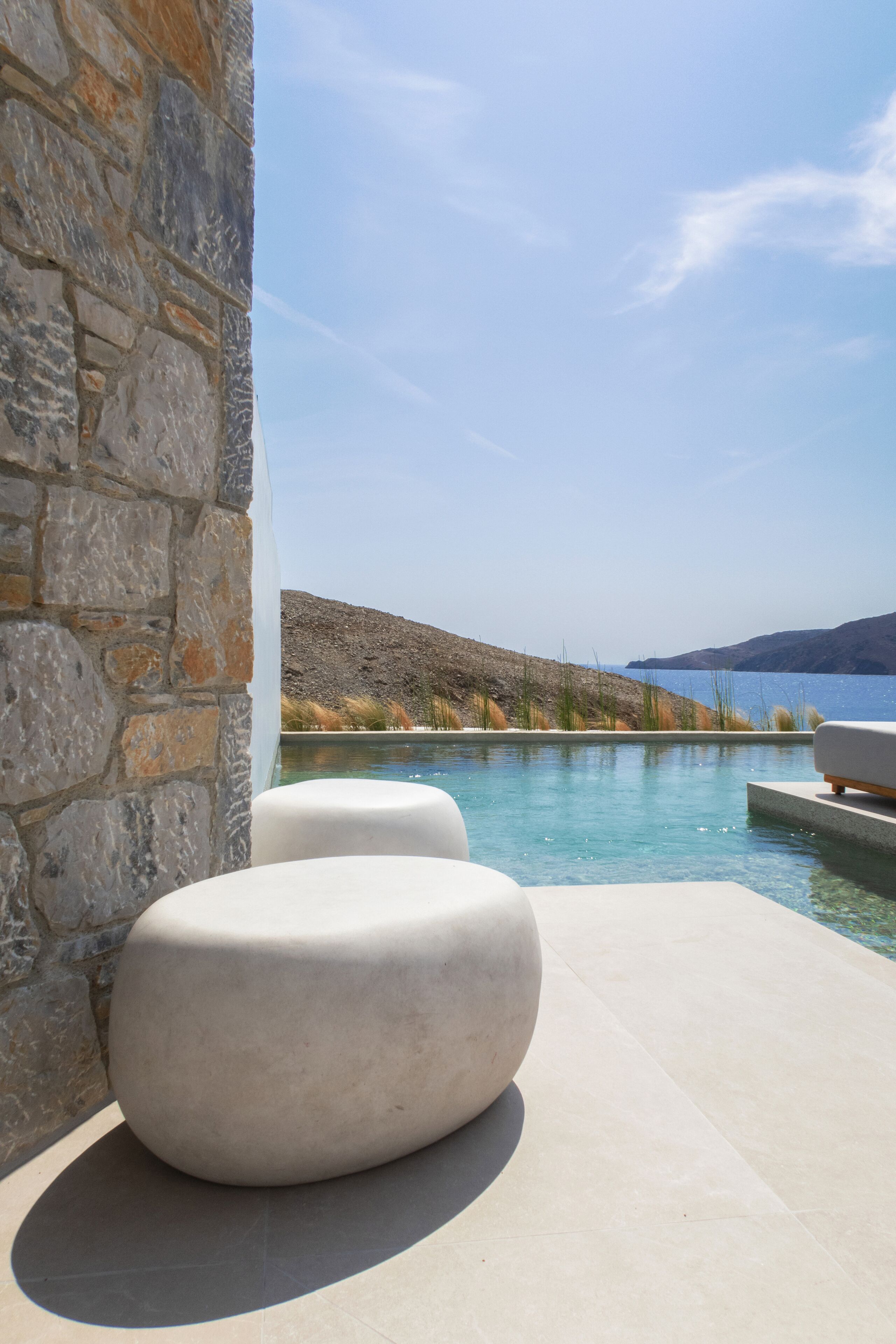Un muro de piedra, una piscina y vista al mar.