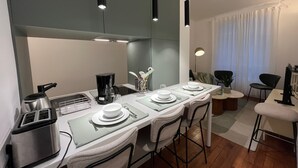 A modern kitchen with a dining area, equipped with a coffee maker, toaster, and bar stools. - Standing - Place des Vosges - Chambre au Calme (Paris)
