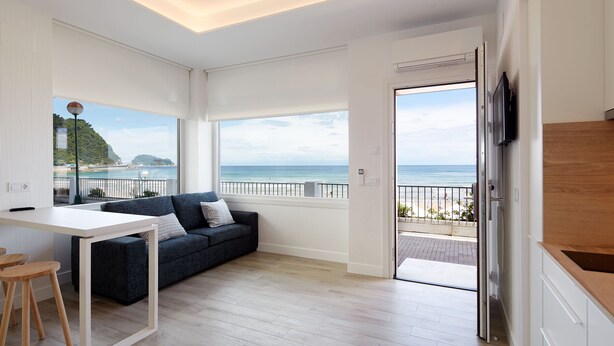 Een moderne woonkamer met uitzicht op zee, met een bank, een eettafel en een keuken.