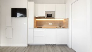 Een moderne keuken met witte kasten, een ingebouwde magnetron en een houten aanrecht.