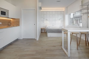 Une chambre à coucher moderne et compacte, comprenant un lit, des tables de chevet et une fenêtre.