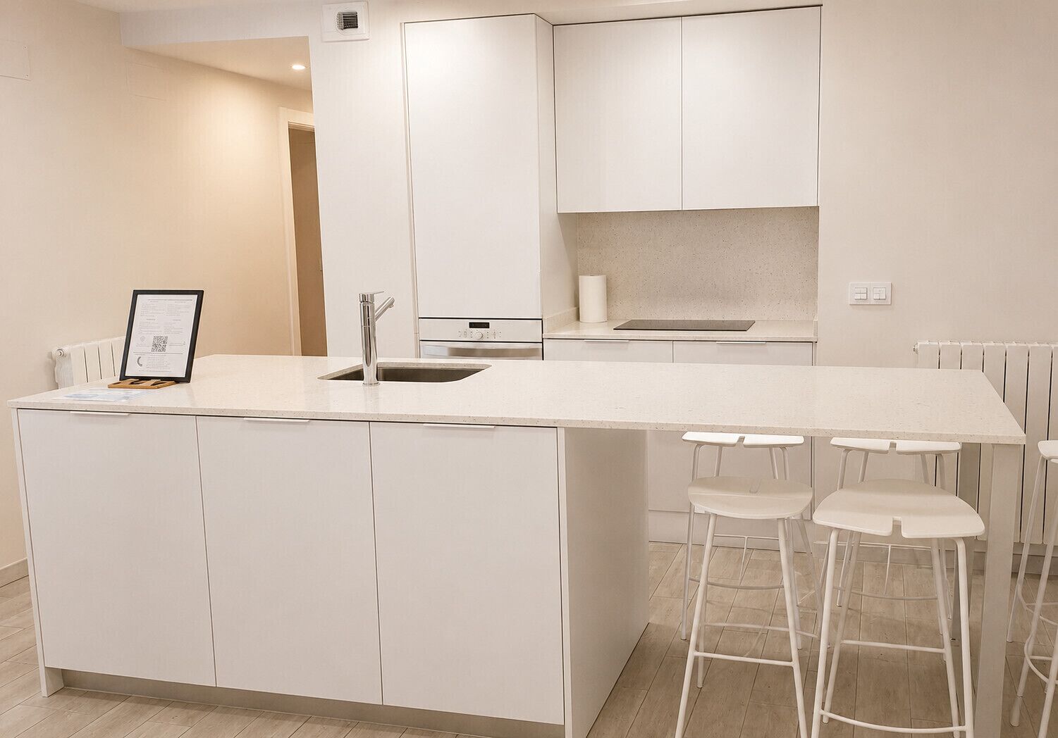 A modern kitchen with a central island, bar stools, and a built-in oven.