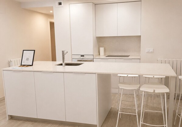A modern kitchen with a central island, bar stools, and a built-in oven.
