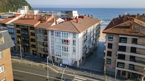 Een kuststedelijk gebied met meerhoogbouwwoningen, een helder uitzicht op zee en een straat met duidelijke wegmarkeringen.