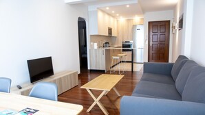 Een moderne woonkamer met een bank, een televisie en een eettafel.