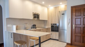Een moderne keuken met een centraal eiland, roestvrijstalen apparatuur en houten kastjes.
