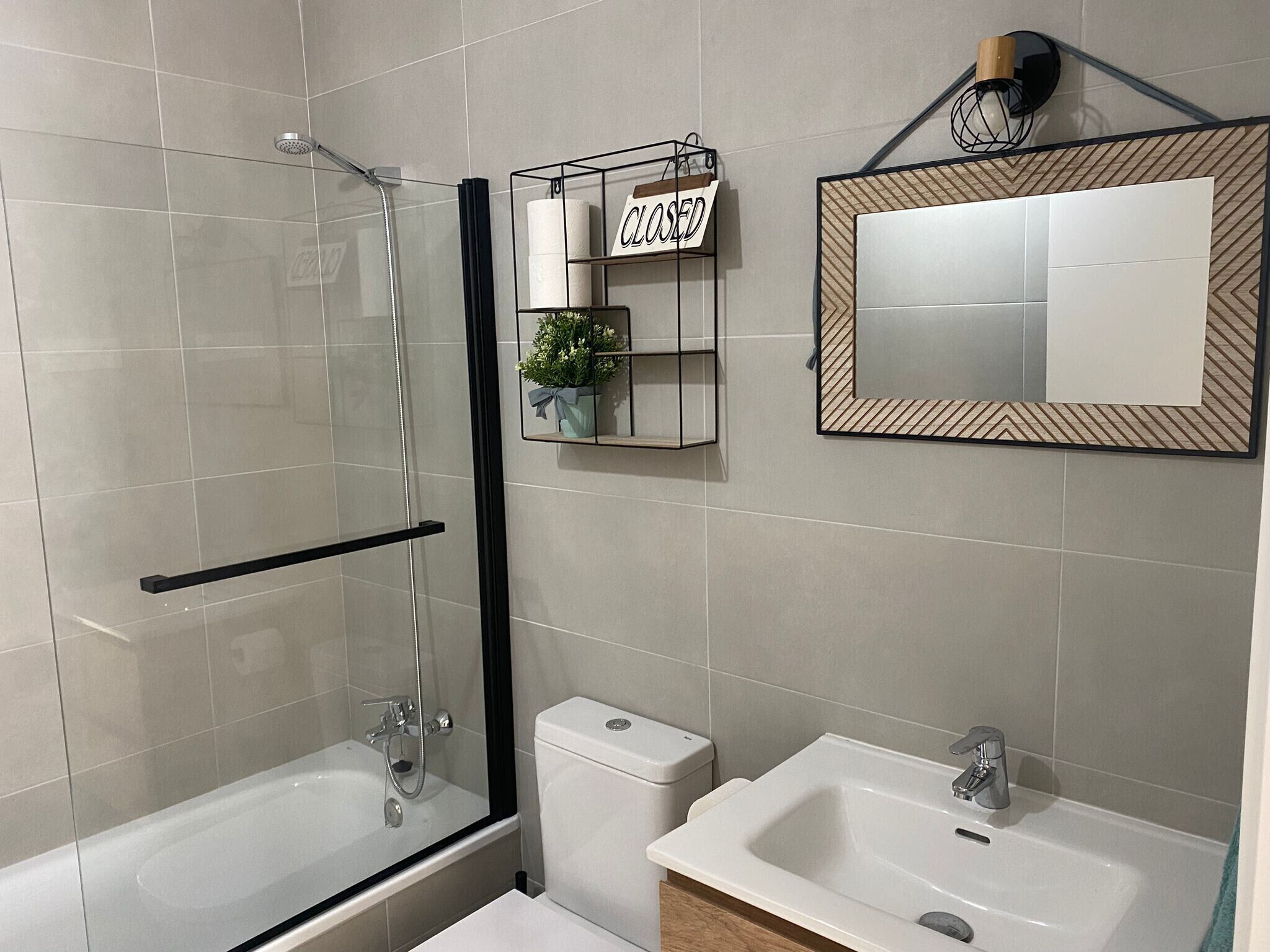 A modern bathroom with a glass-enclosed shower, a toilet, and a sink.