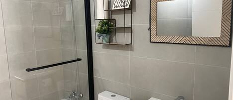 A modern bathroom with a glass-enclosed shower, a toilet, and a sink.