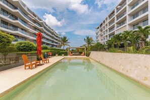 A modern hotel with a swimming pool, outdoor seating, and palm trees. - w* | Amazing 2BR with Terrace in Manzanillo Beach (Cartagena de Indias)