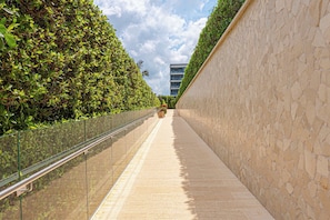 A narrow pathway flanked by a glass railing and a stone wall, leading to a building with a modern design. - w* | Amazing 2BR with Terrace in Manzanillo Beach (Cartagena de Indias)