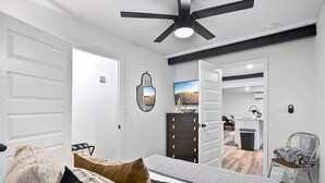 A bedroom with a bed, a dresser, a chair, and a ceiling fan. - Renovated Bungalow with Work Space, Kitchen, Patio (St. Augustine)