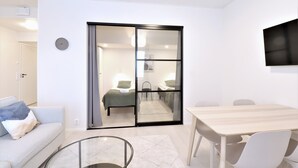 Quarto moderno com cama, sofá, mesa de jantar e televisão.