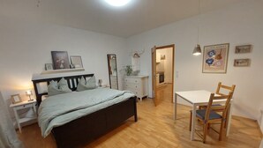 A bedroom with a bed, bedside table, dresser, and a small table with a chair. - Moderne Ferienwohnung mit Eigener Terrasse (Arnsberg)