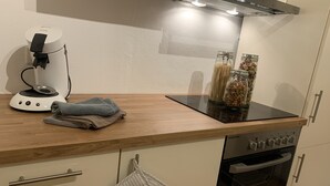A modern kitchen with a built-in stove, a coffee maker, and jars of pasta. - Moderne Ferienwohnung mit Eigener Terrasse (Arnsberg)