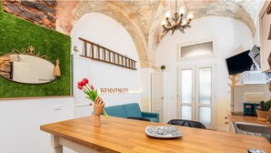 A modern living room with a wooden table, a blue sofa, and a chandelier. - Casa Nirè - Casa Nirè II - Casa di Tano (Catania)