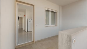 A room with a tiled floor, a door leading to another room, and a window with curtains. - 3768 Appartamento La Playa by Barbarhouse (Porto Cesareo)