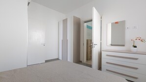 A bedroom with a bed, a dresser, a mirror, and a door leading to another room. - 3768 Appartamento La Playa by Barbarhouse (Porto Cesareo)