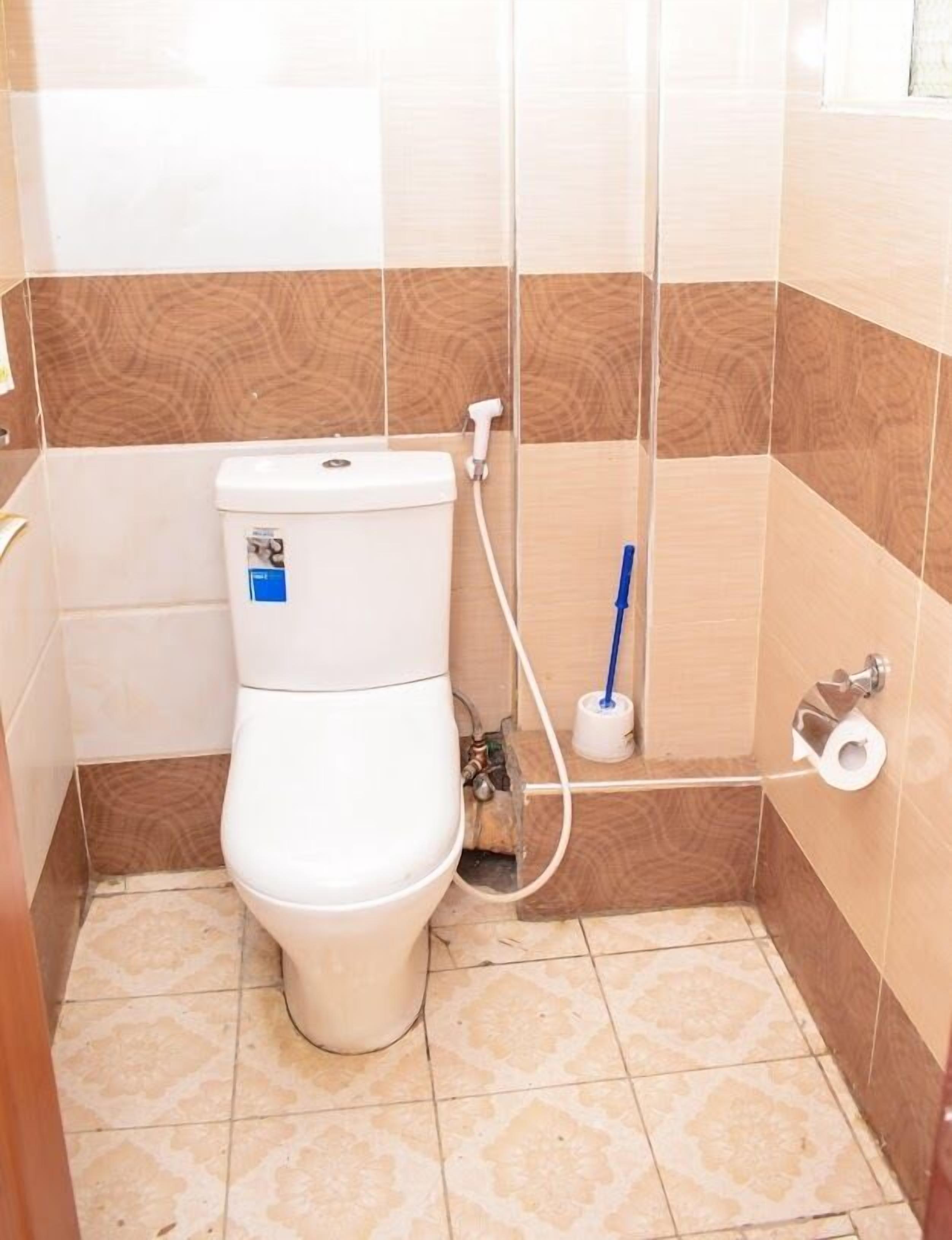 Un baño pequeño con inodoro, dispensador de papel higiénico y secamanos.