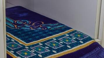 A bed with a blue and purple patterned blanket.