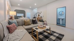 Ett modernt vardagsrum med en soffa, ett soffbord och utsikt över badrummet.