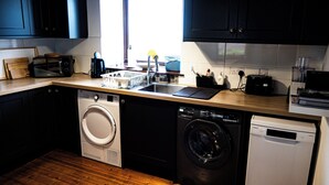 Une cuisine compacte équipée d’un lave-linge, d’un lave-vaisselle et d’un four à micro-ondes.