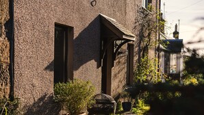 Un bâtiment de style rustique, doté d’une façade à la texture particulière, d’une porte en bois et d’un petit porche.